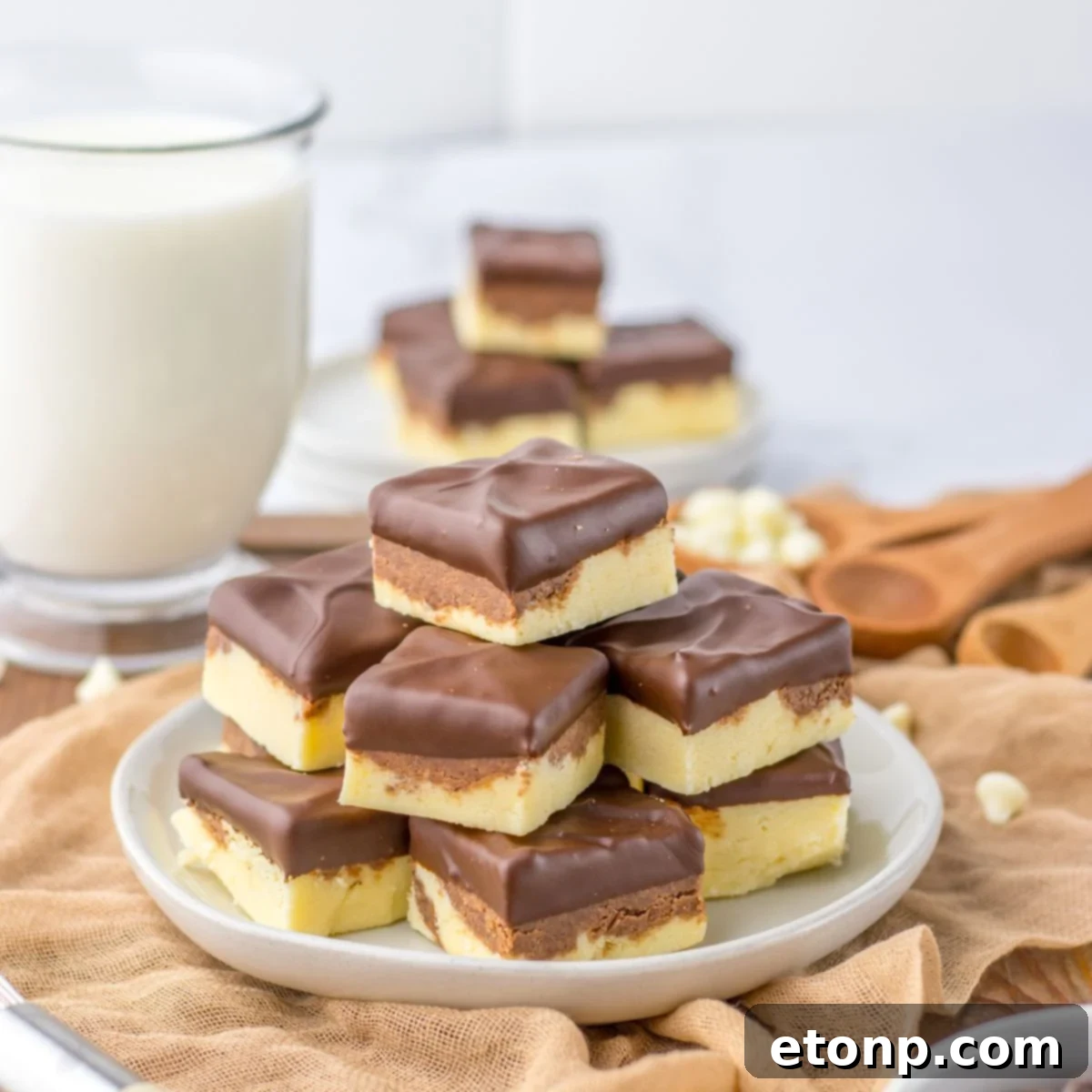 Boston Cream Pie Fudge stacked on table with glass of milk behind it