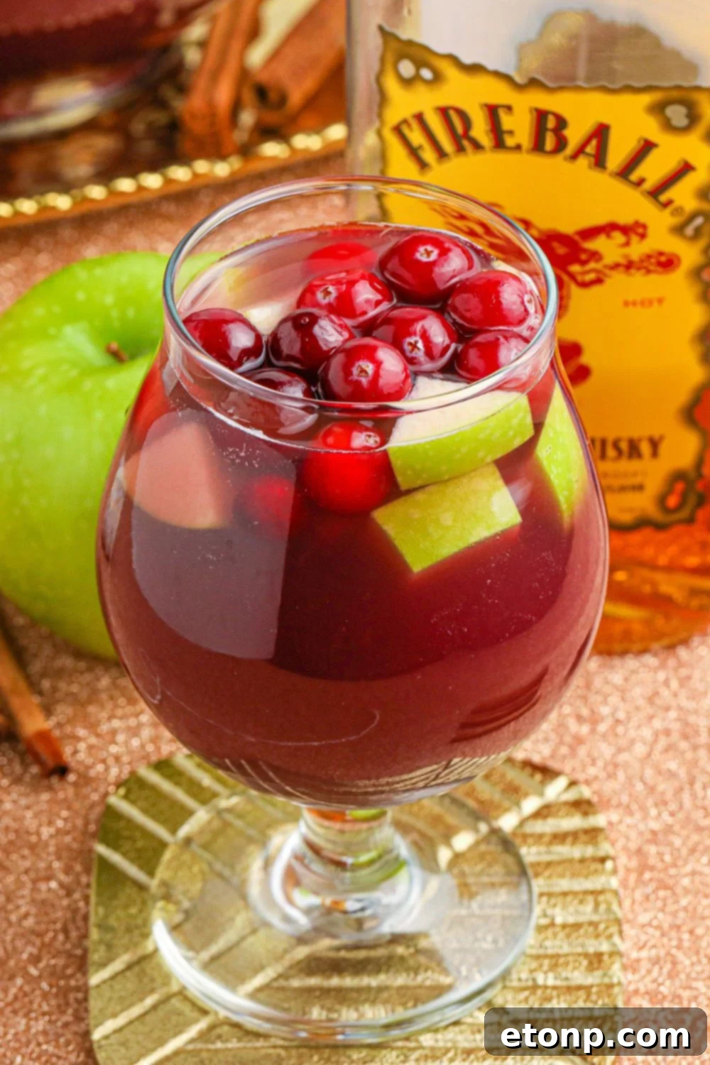 Cinnamon Spice Sangria 11 An array of Fireball Sangria glasses and a pitcher with fresh fruit on a table, with a bottle of Fireball whiskey in the background, creating a festive atmosphere.