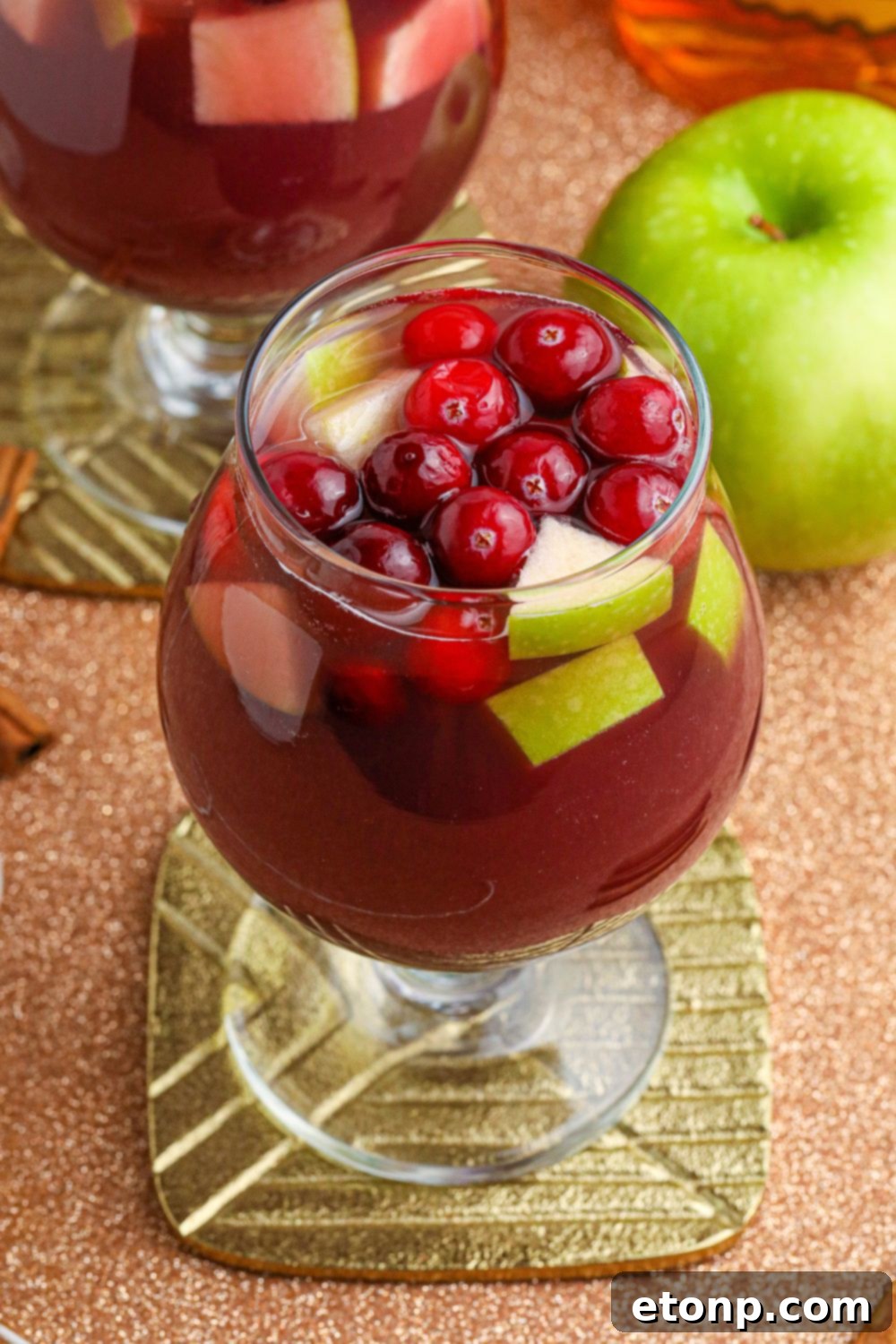 Cinnamon Spice Sangria 13 A Fireball Sangria cocktail on a coaster, with a fresh apple in the background, highlighting its refreshing qualities.