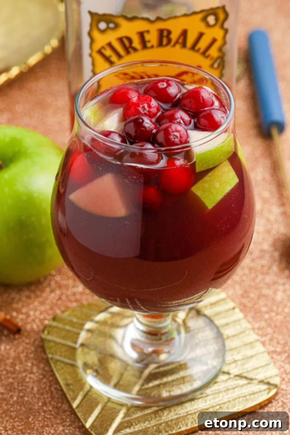 Cinnamon Spice Sangria 4 A single glass of Fireball Sangria, showcasing the rich color and fruit, resting on a wooden coaster.