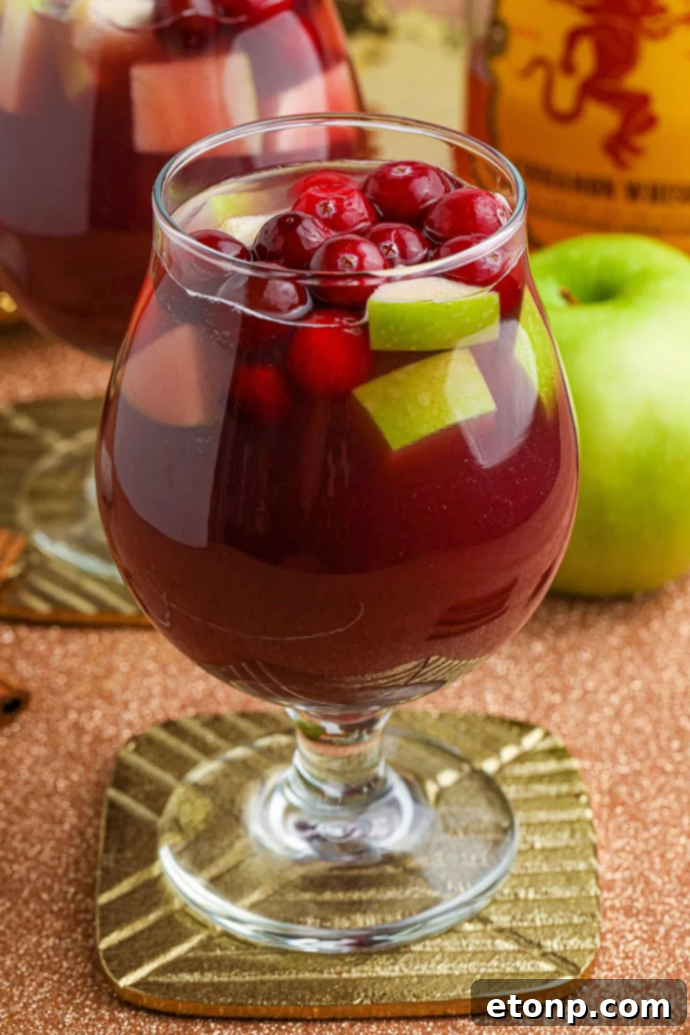 Cinnamon Spice Sangria 7 A side view of Fireball Sangria in a wine glass on a table, highlighting its inviting color and fruit content.