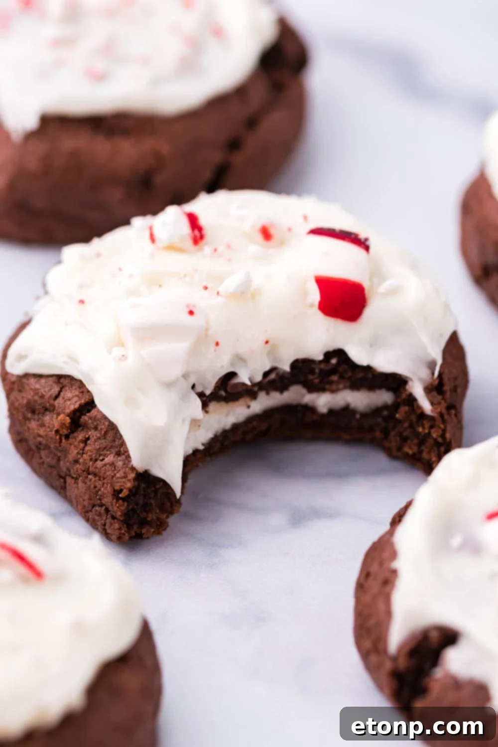 Molten Peppermint Patty Chocolate Cookies 6 A single peppermint patty cookie with a bite taken out, sitting on a marble table surrounded by other cookies