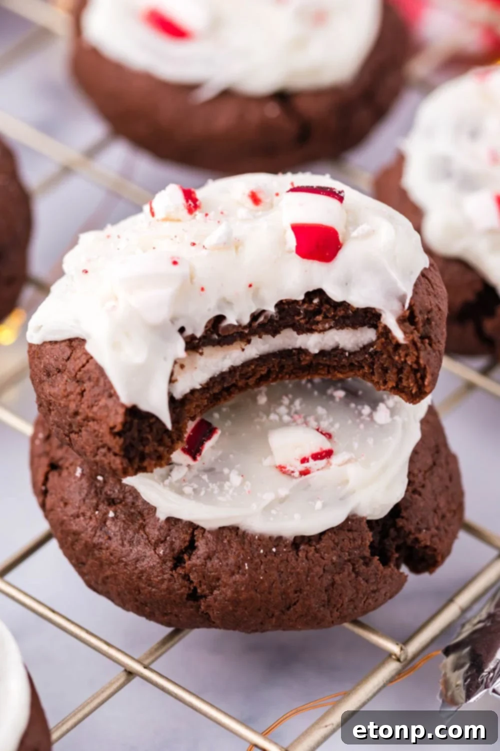 Molten Peppermint Patty Chocolate Cookies 8 A stack of cookies with one having a bite taken out, showcasing the mint filling