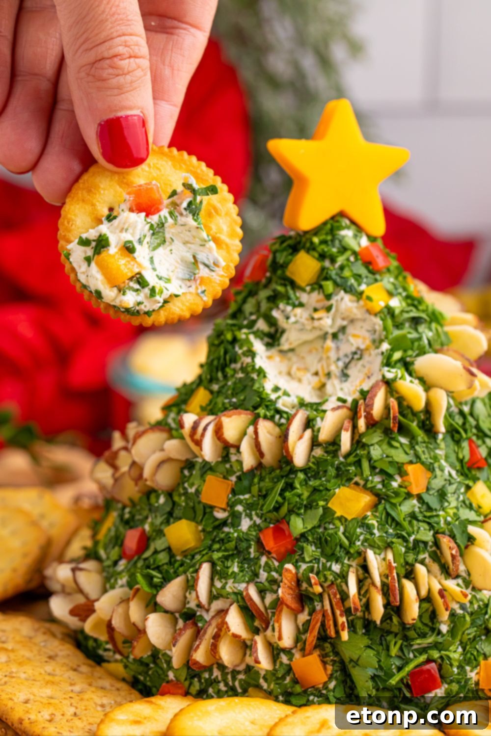 Cracker with a portion of cheeseball on it, held by a hand