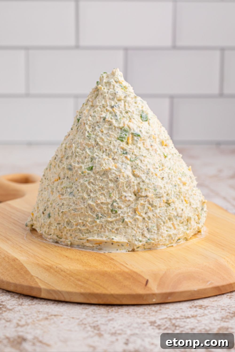 Dome-shaped cheeseball on a wooden cutting board before decorating