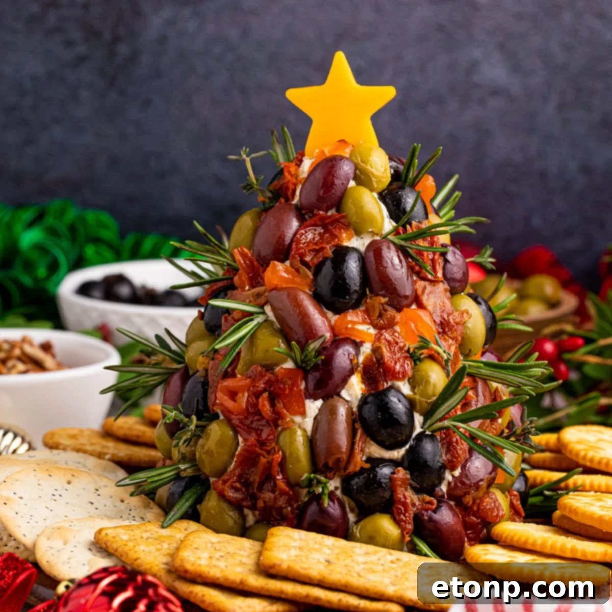 Antipasto Christmas Tree cheese ball beautifully displayed on a table surrounded by an array of crackers, ready for holiday entertaining.