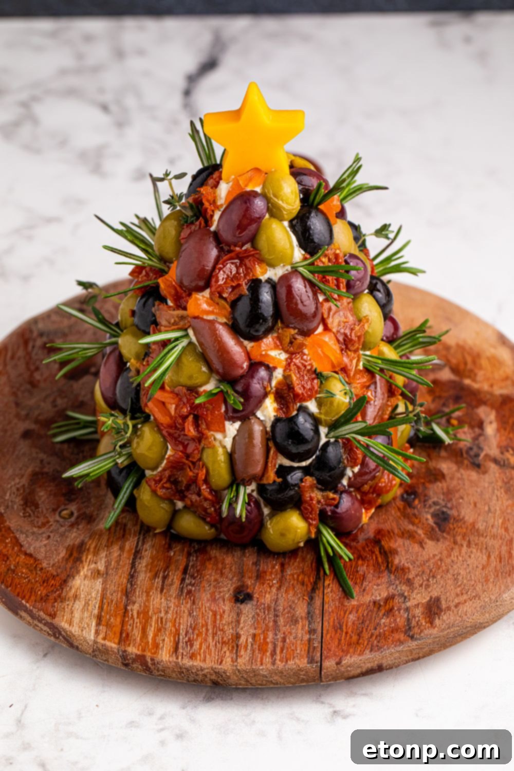 An overhead view of the perfectly shaped cheeseball on a round cutting board, awaiting its festive decorations.