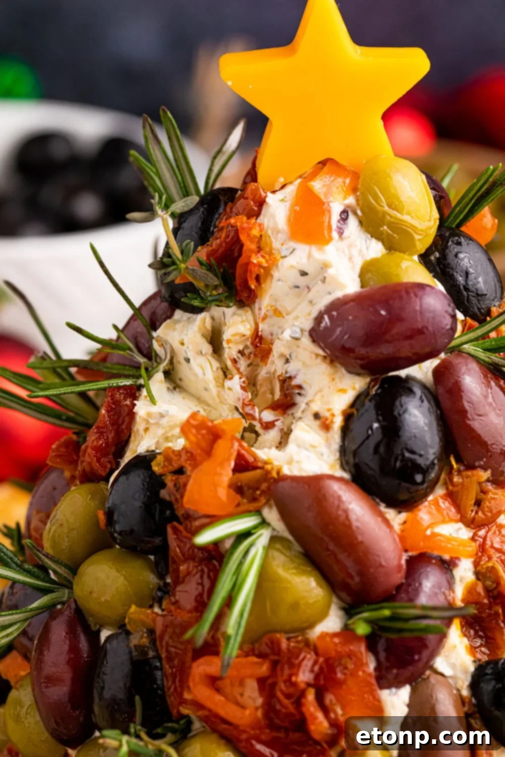 A delightful Christmas cheese ball displayed on a table, with a portion already removed, showing its creamy interior and inviting texture.