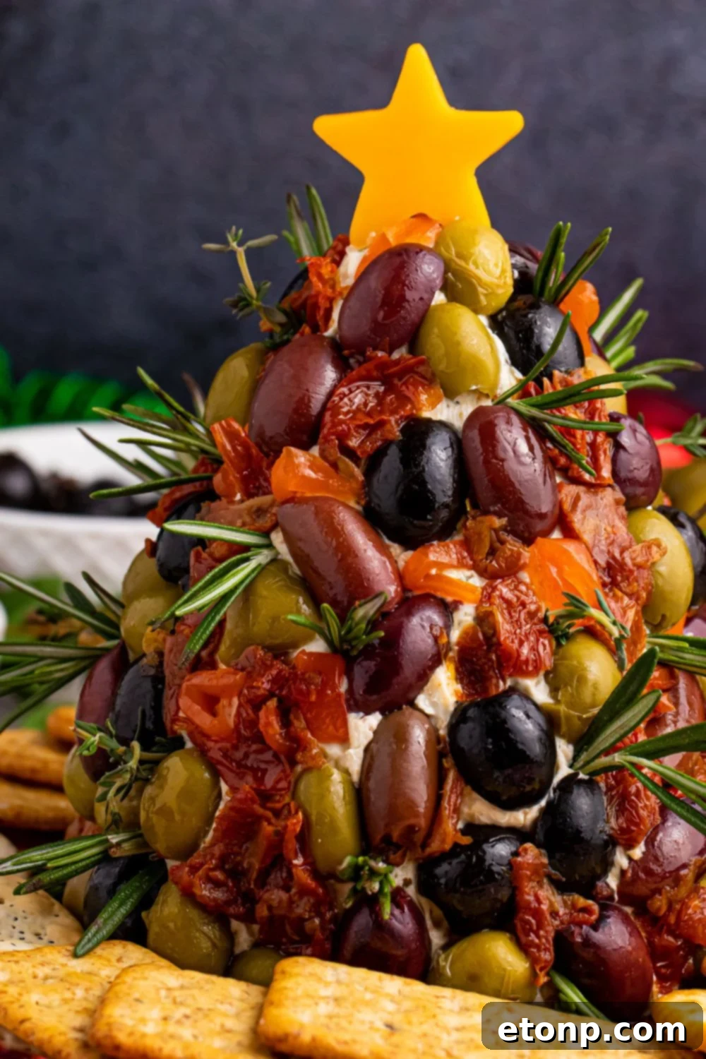 A beautifully crafted cheese dip shaped like a Christmas tree, surrounded by an array of crackers on a table, ready for holiday enjoyment.
