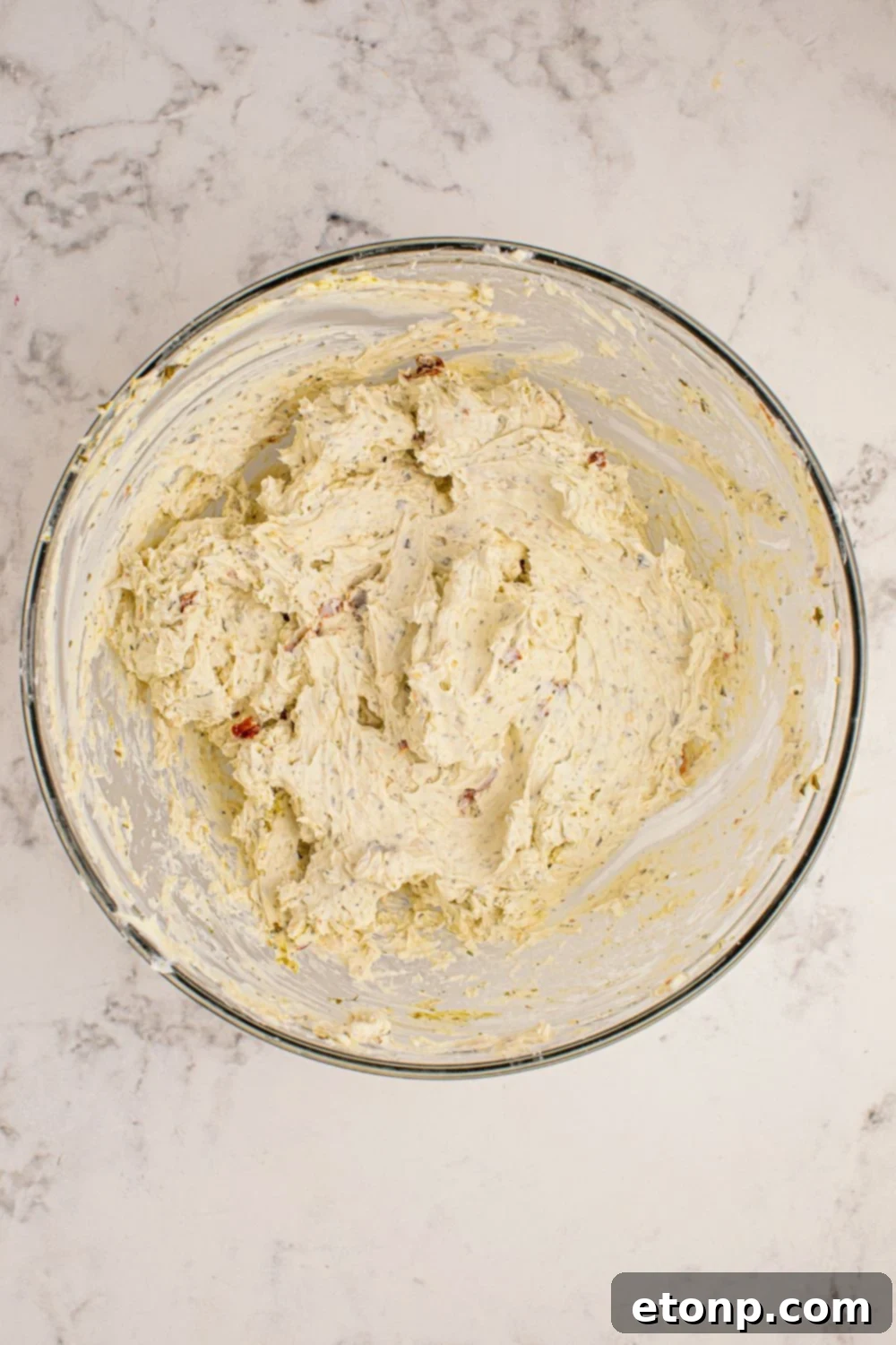 A glass bowl filled with the creamy, herb-infused cheeseball mixture, ready for shaping.