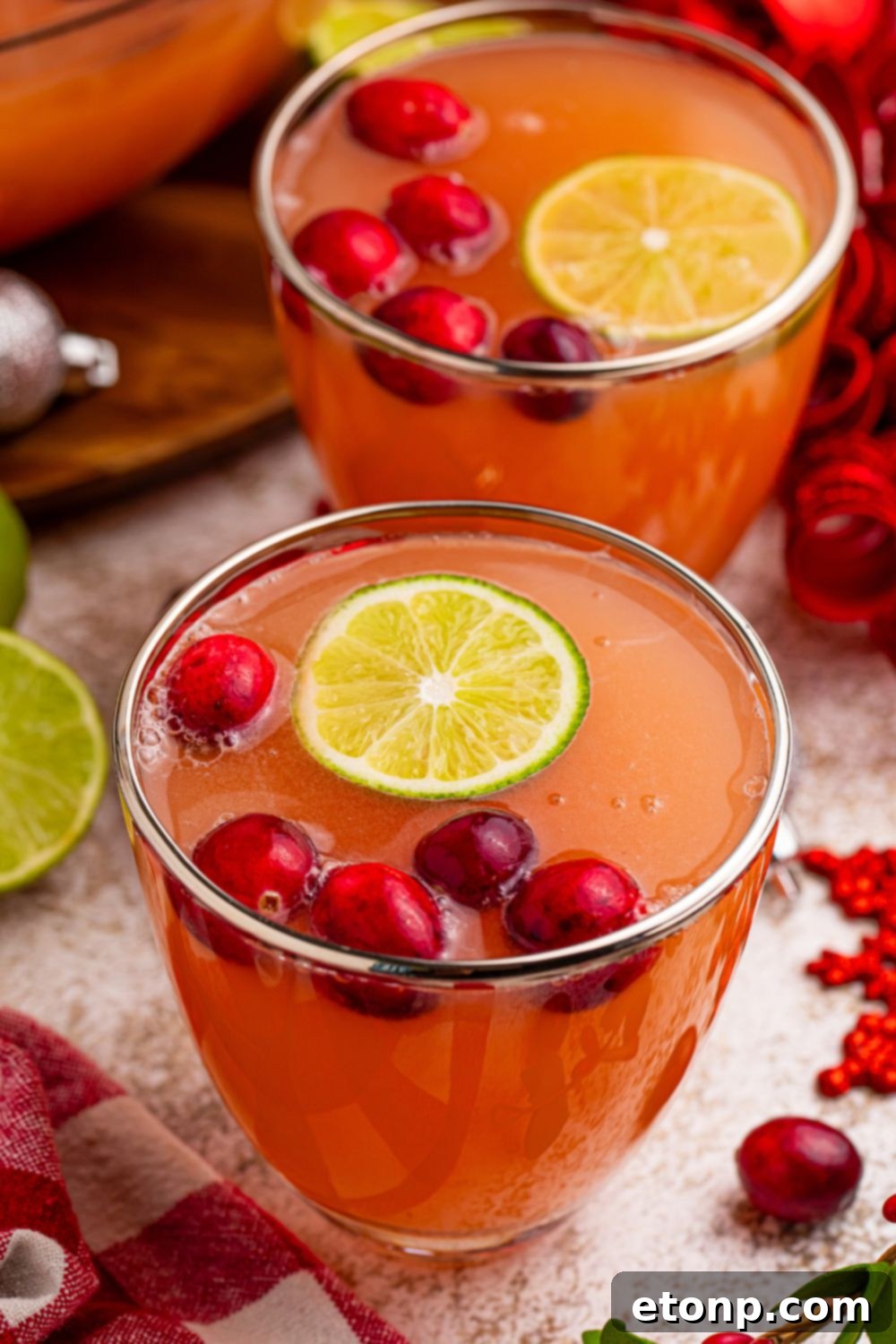 A single glass of Santa's Giggle Juice Punch, garnished with fresh cranberries and a lime slice, resting on a textured tabletop, invitingly cold and refreshing.
