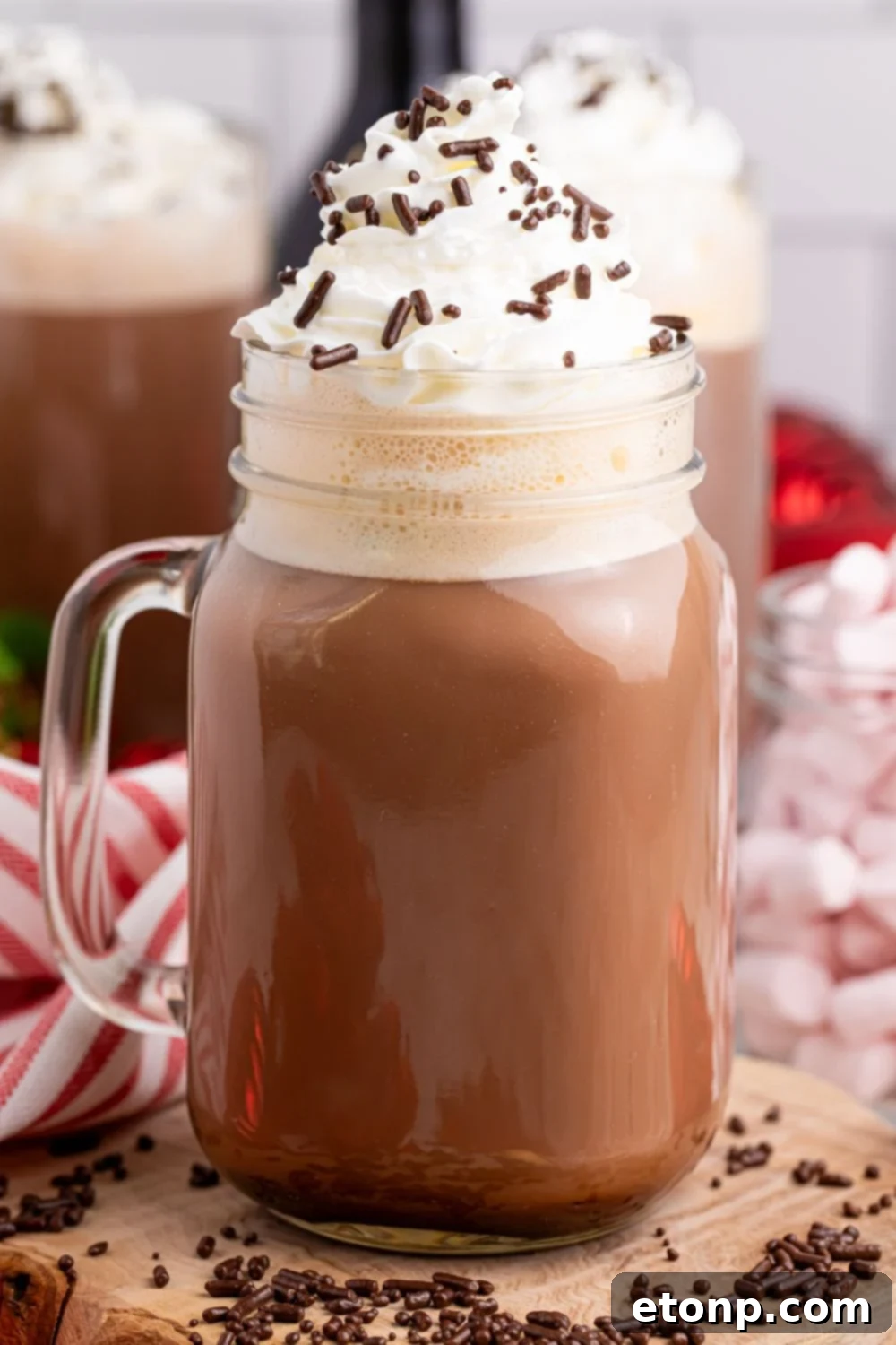 Naughty Snowman's Brew 10 hot chocolate drink on table with whipped cream and sprinkles and then sprinkles around the glass on table