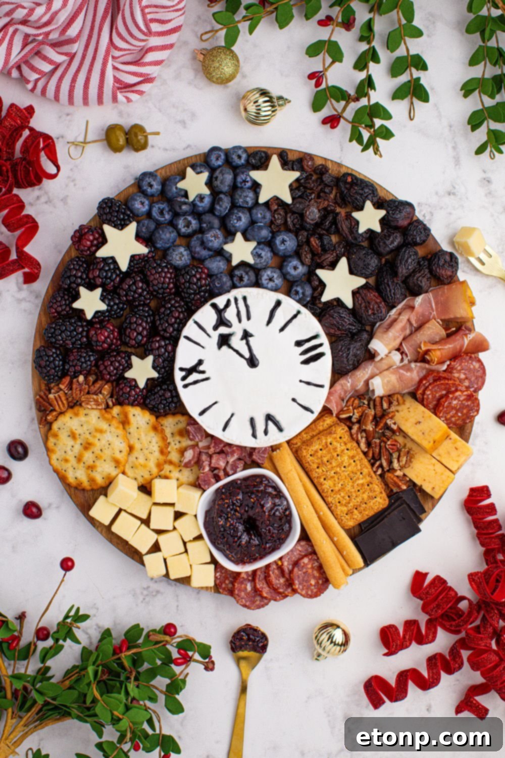New Year's Eve Charcuterie Board with garnishes of fresh herbs, berries, and more on table 