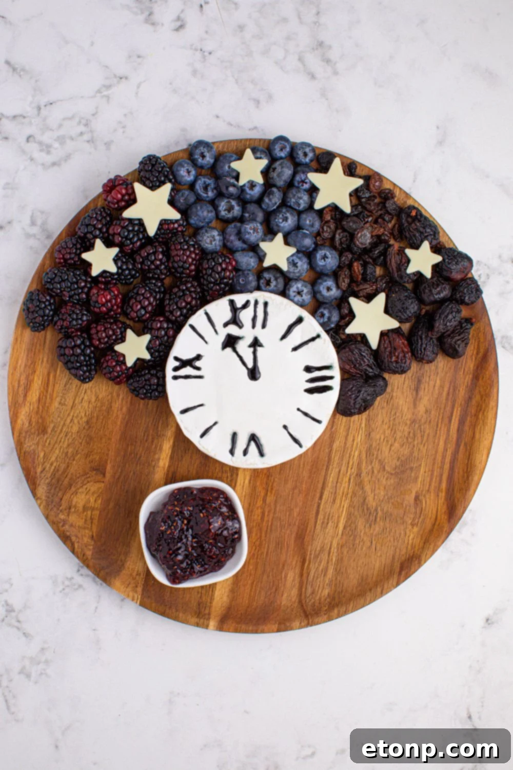 berries and a brie block on a round cutting board showing how to assemble a charcuterie board 