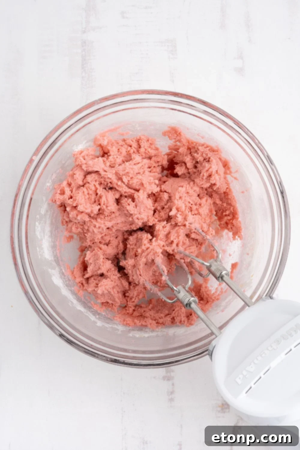 Cherry Chocolate Chip Cookie dough that is colored pink and being mixed with a hand mixer 