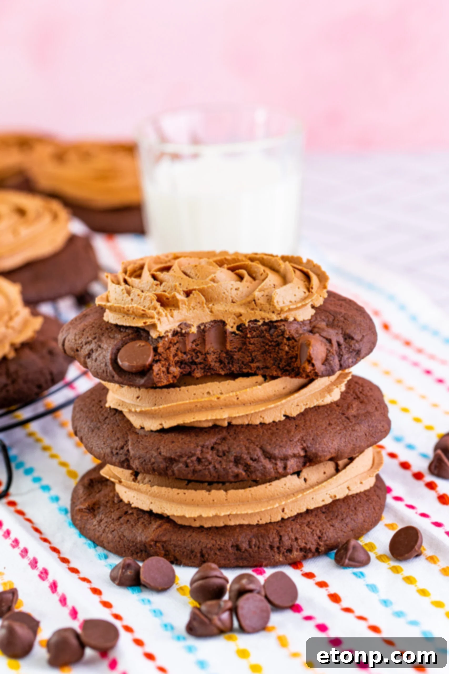 Decadent Chocolate Cake Cookies 2 Stacked soft-baked chocolate cake cookies with thick chocolate fudge frosting, a bite missing from the top cookie revealing its moist interior.