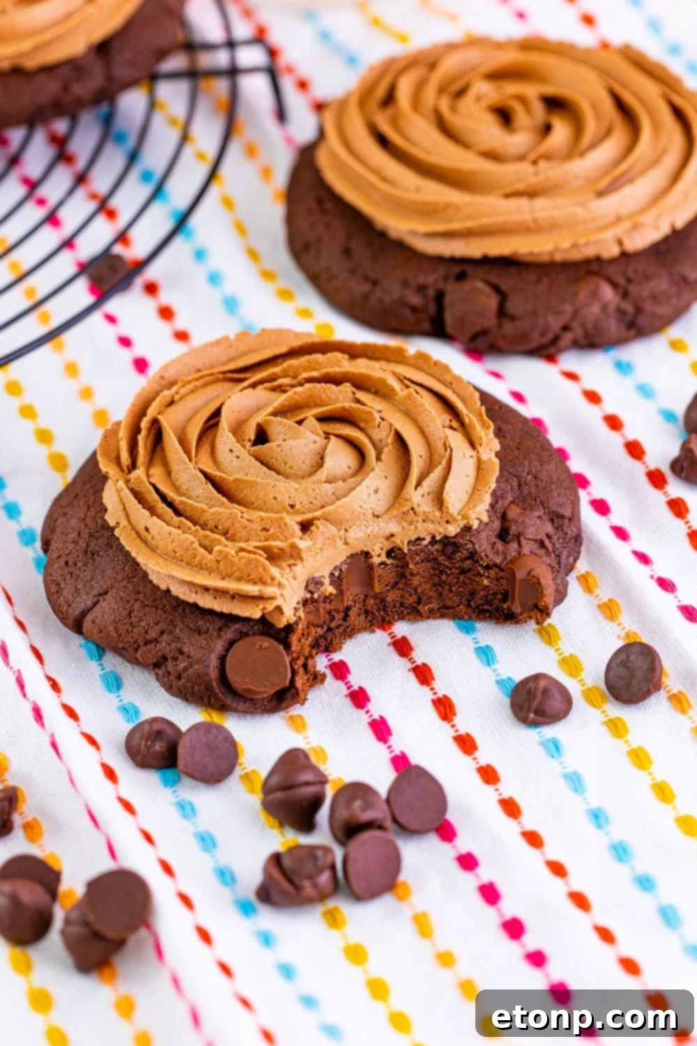 Decadent Chocolate Cake Cookies 18 A chocolate cake cookie on a table with a bite taken out, surrounded by scattered mini chocolate chips, emphasizing its deliciousness.