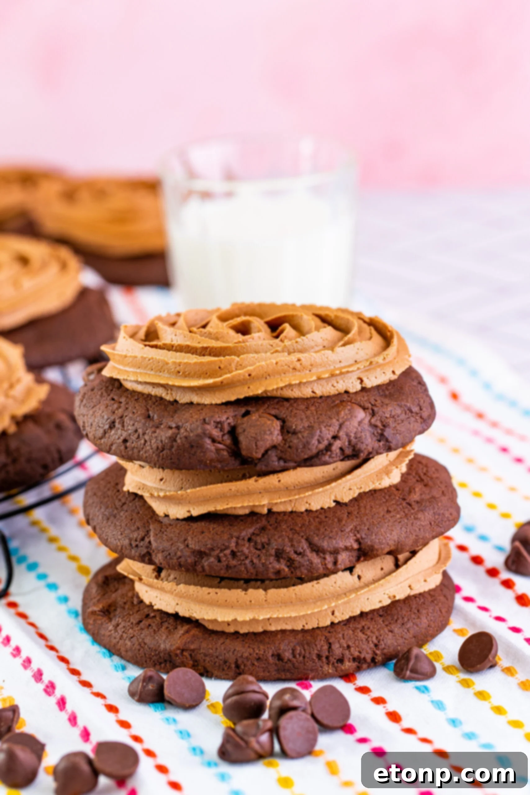 Decadent Chocolate Cake Cookies 20 Stacked chocolate cake cookies with chocolate fudge frosting, with a glass of milk in the background, a classic cookie pairing.