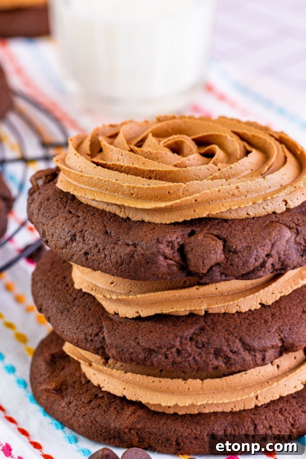 Decadent Chocolate Cake Cookies 4 Several frosted chocolate cake cookies stacked neatly on a rustic wooden table, ready to be served.