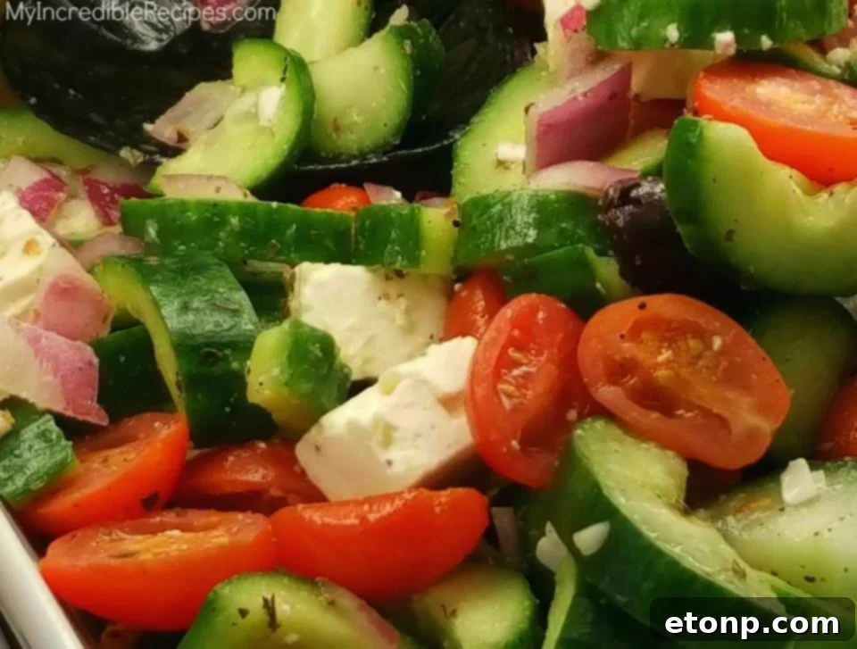 Delicious and fresh Greek Cucumber Salad with tomatoes, cucumbers, feta, and olives in a bowl, perfect for a party or healthy meal.