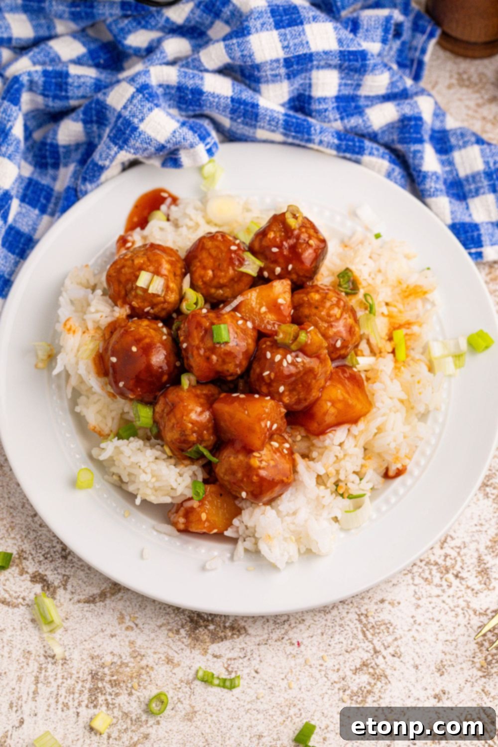 Slow Cooker 3 Ingredient Hawaiian Meatballs on a white plate with white rice and sesame seeds on the top of meatballs 