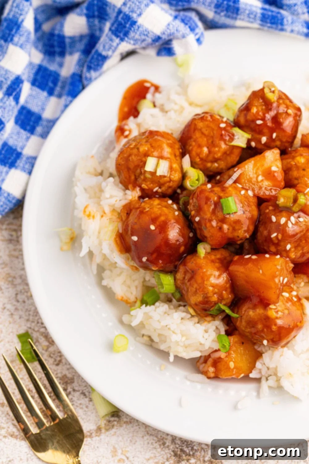 Slow Cooker 3 Ingredient Hawaiian Meatballs on plate with a fork and blue napkin placed on side of plate 