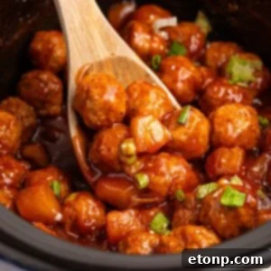 Slow Cooker 3 Ingredient Hawaiian Meatballs in a crockpot with a wooden spoon with some on it