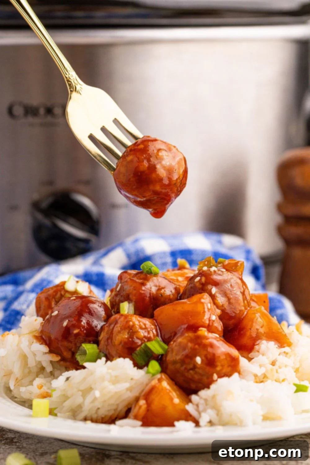 Slow Cooker 3 Ingredient Hawaiian Meatballs on a plate with rice and one poked on a fork above plate 