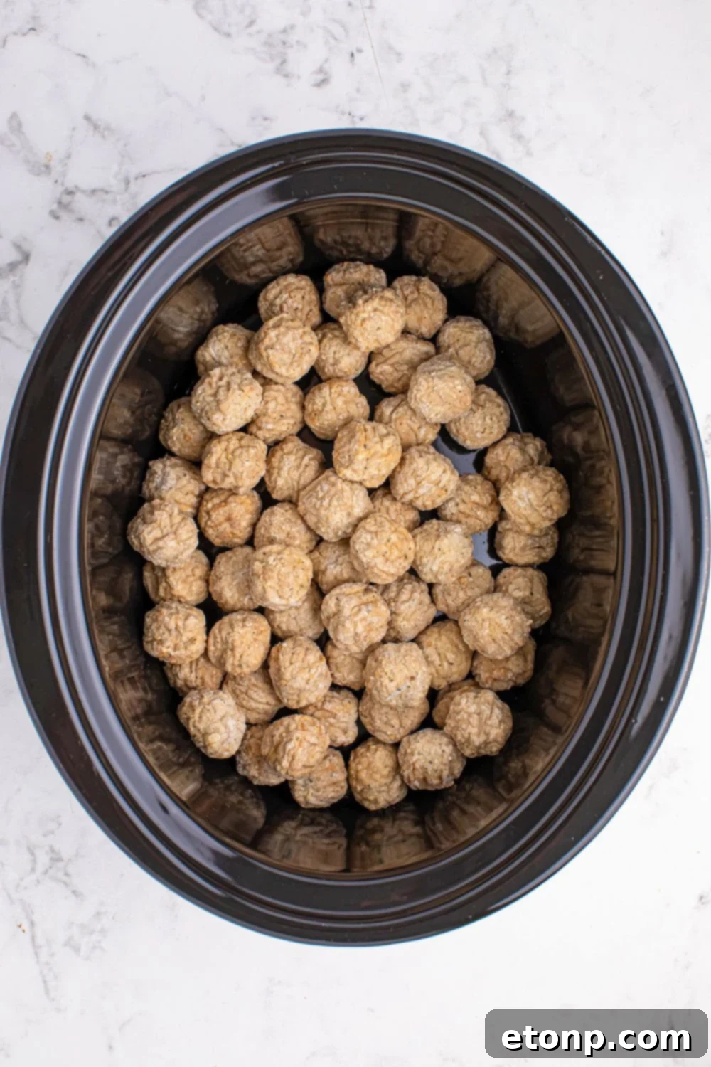 frozen meatballs in a slow cooker on the table 