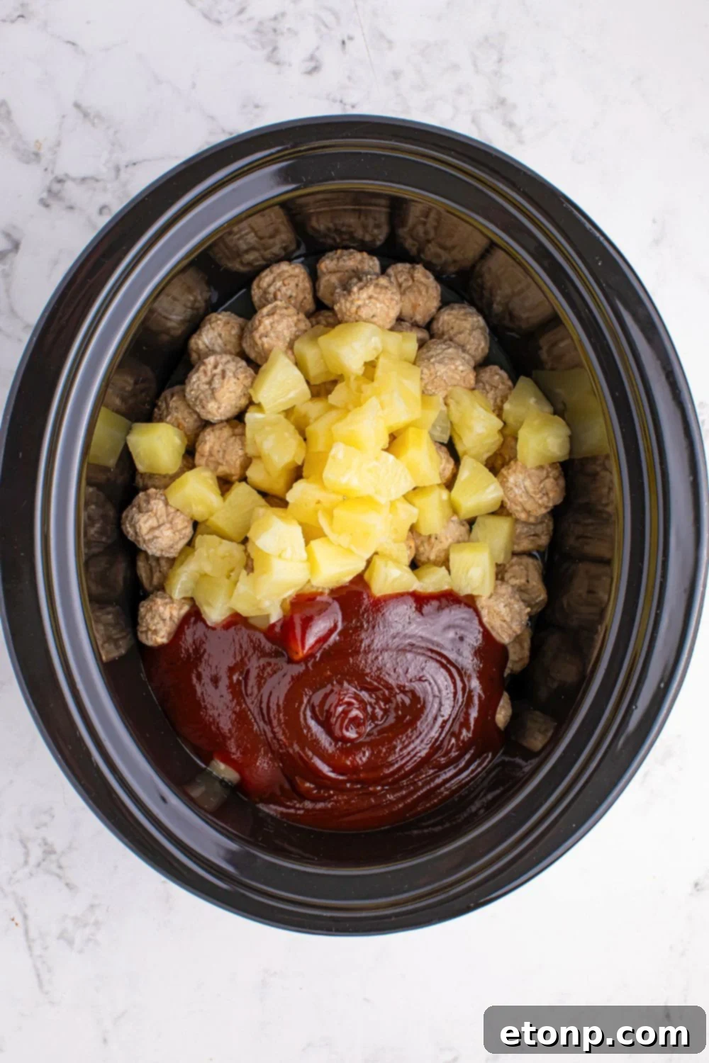 Slow Cooker 3 Ingredient Hawaiian Meatballs in a crockpot with pineapple, sauce, and meatballs inside 