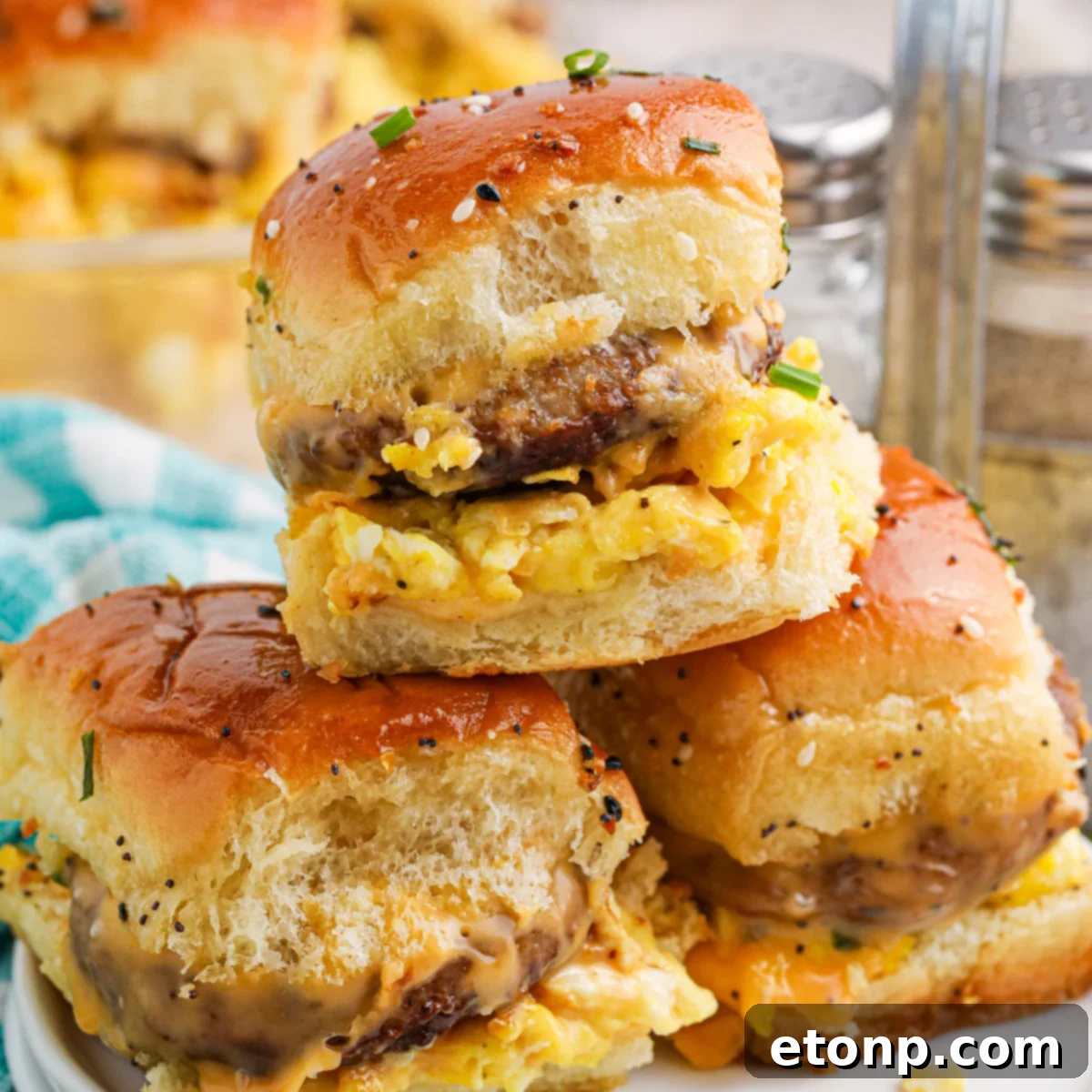 Fully Loaded Cheesy Breakfast Sliders with Sausage stacked on a white plate