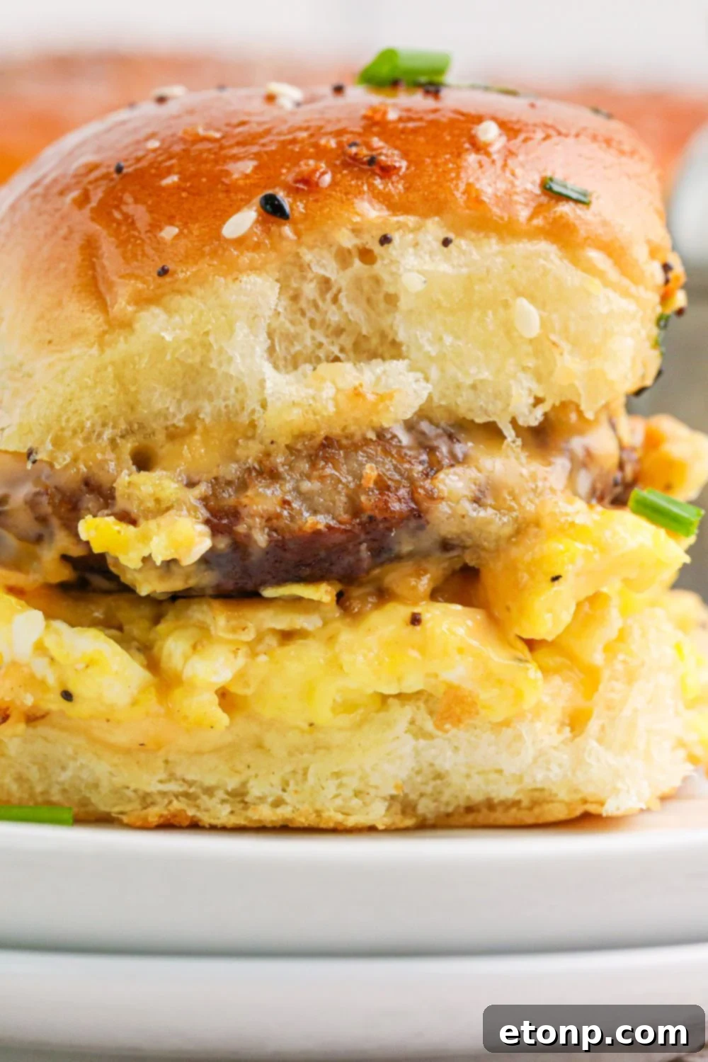 Breakfast Slider on plate with a close up view of the sausage and eggs in the sandwich 