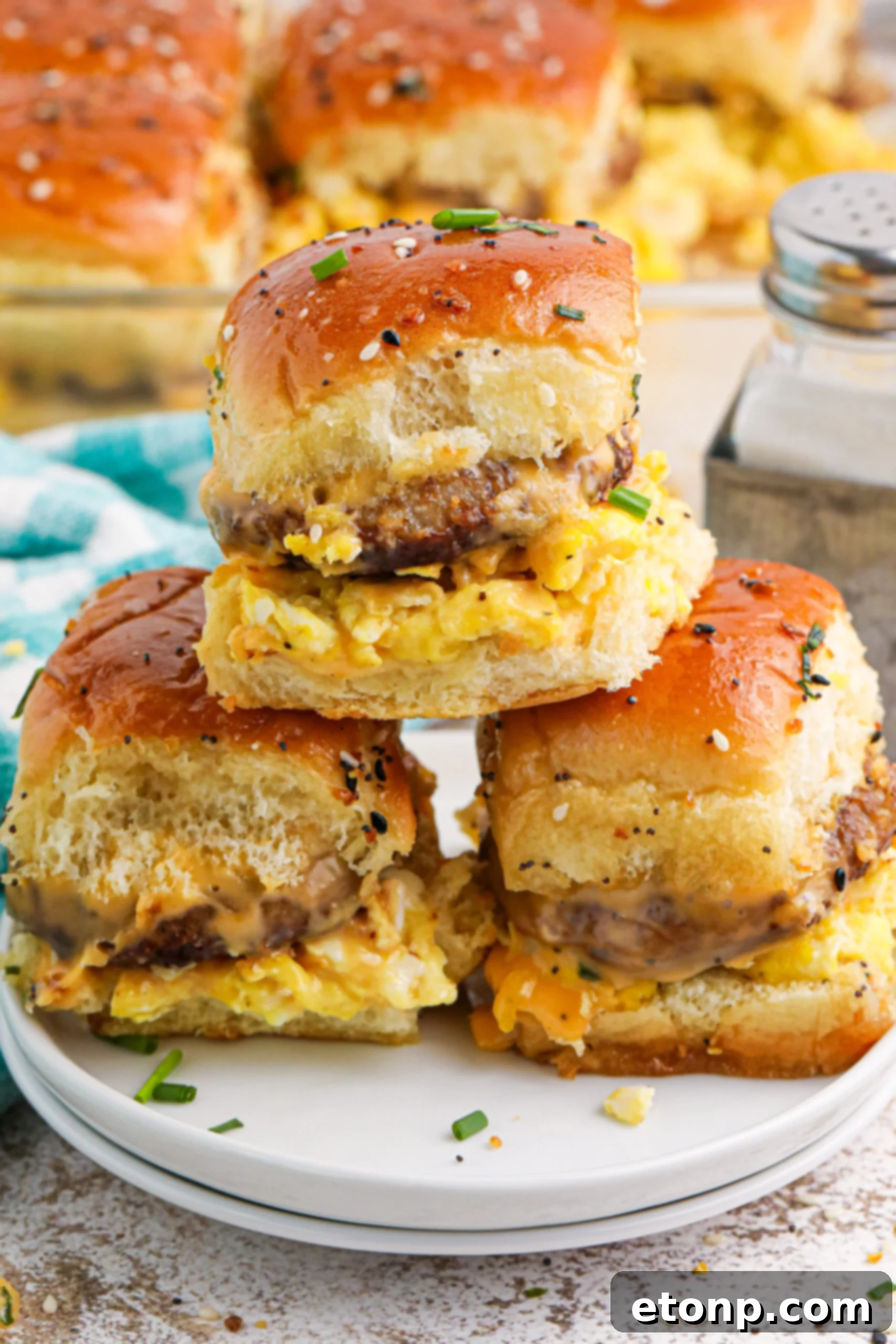 Breakfast Sliders on a plate with some fresh herbs sprinkled on table in the front 