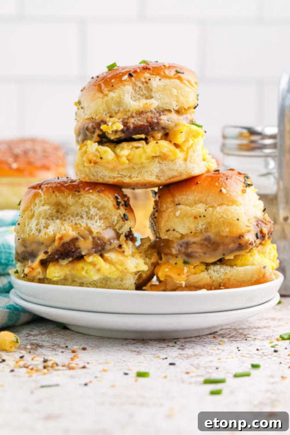 Breakfast Sliders on a plate with some fresh herbs sprinkled on table in the front 