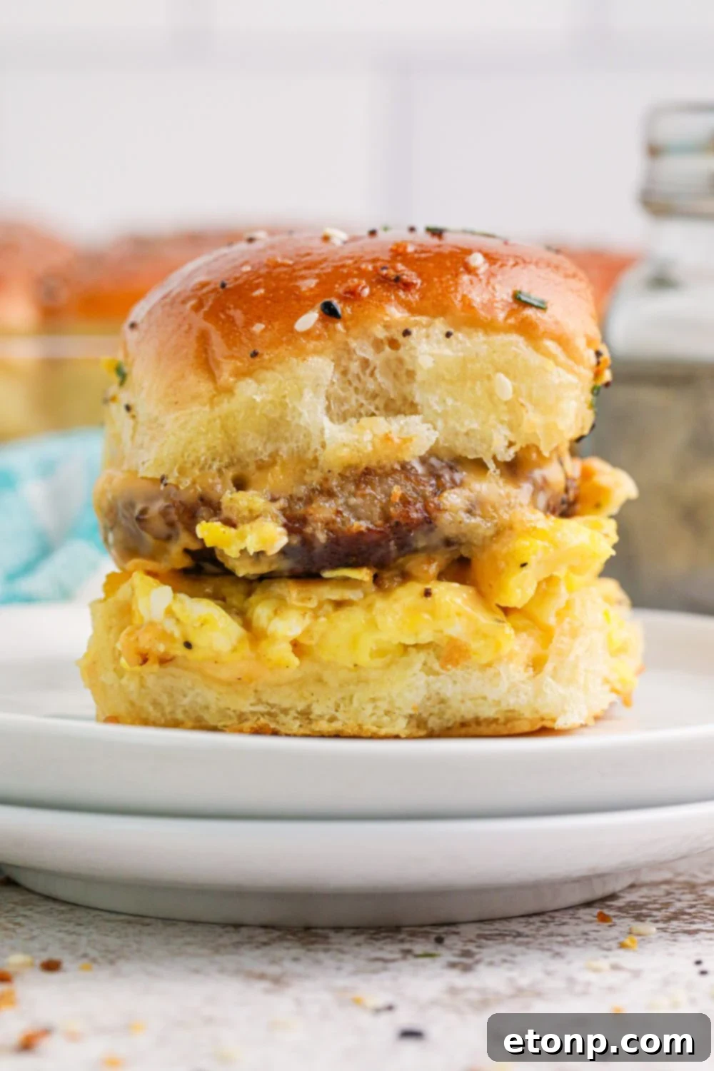 two plates stacked on top of each other with one Breakfast Slider on the plate with egg, cheese and sausage 