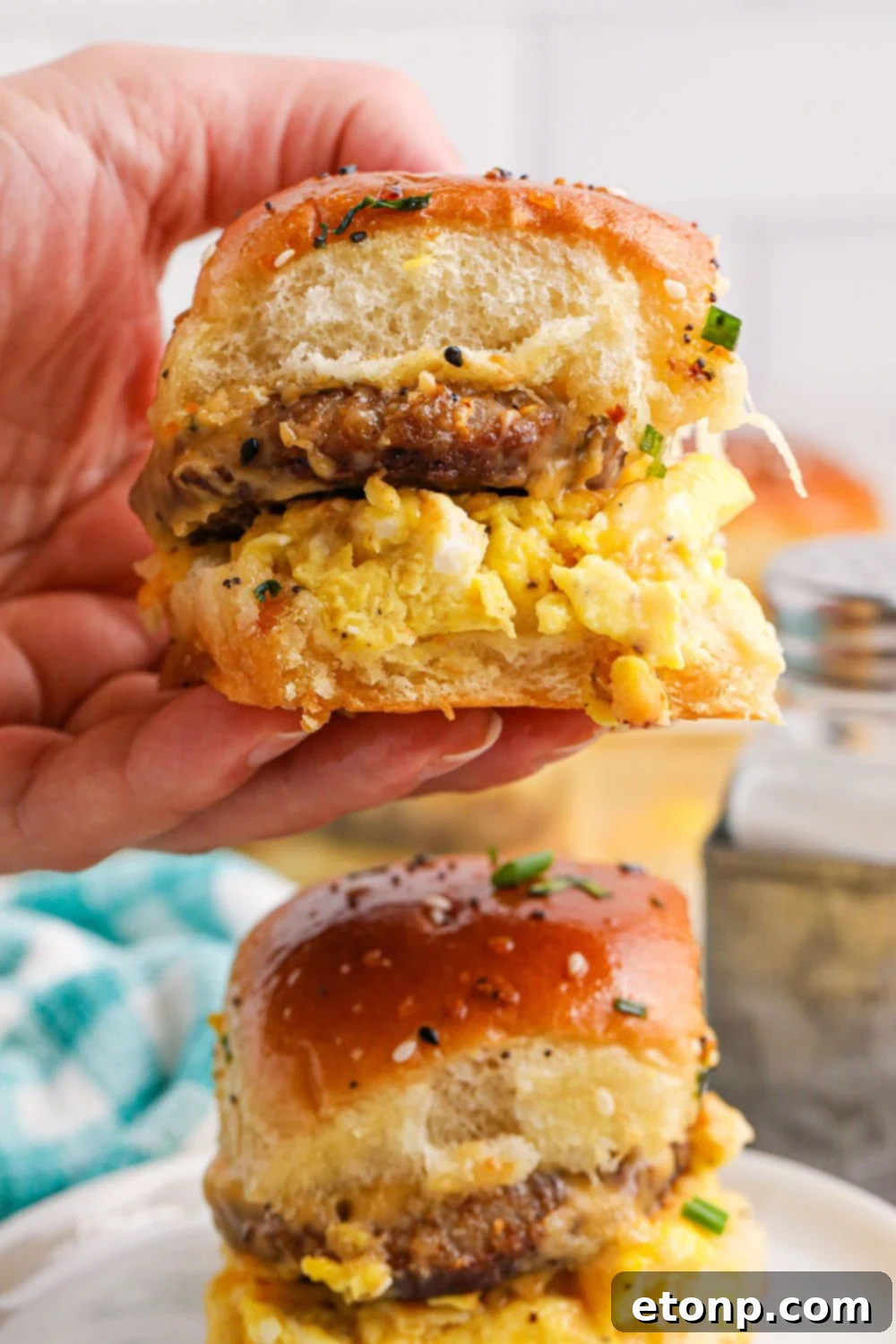 Breakfast Sliders on plate with one being held in a hand 