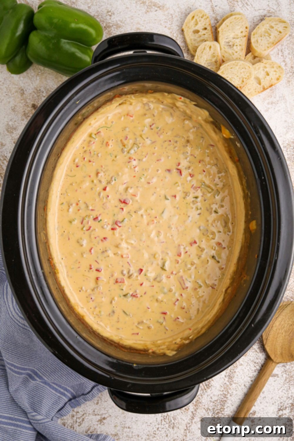 overhead look of Crock Pot Philly Cheesesteak Dip on table with a wooden spatula on the side 