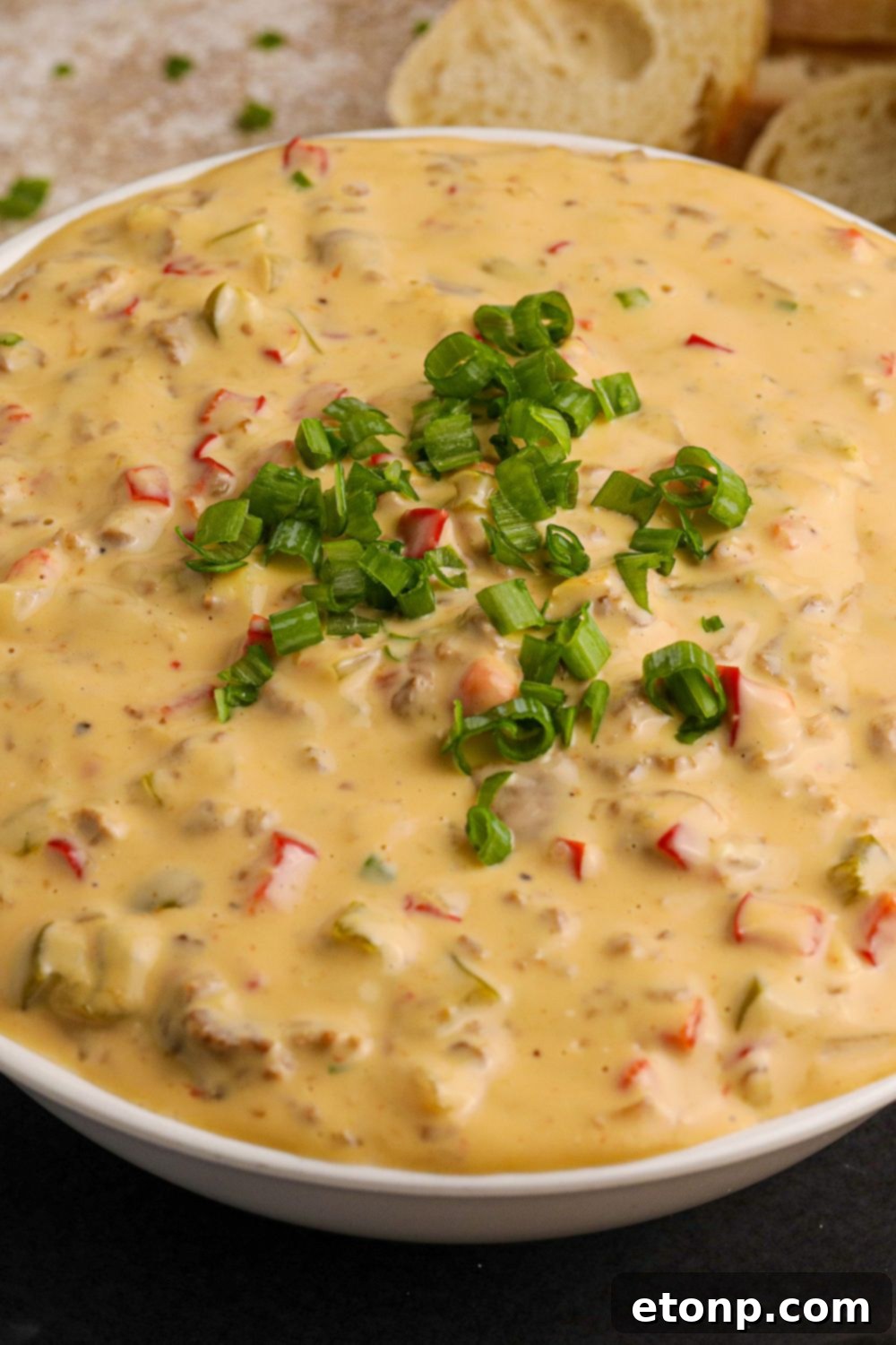 Crock Pot Philly Cheesesteak Dip in a glass bowl with green garnish on top sitting on table 