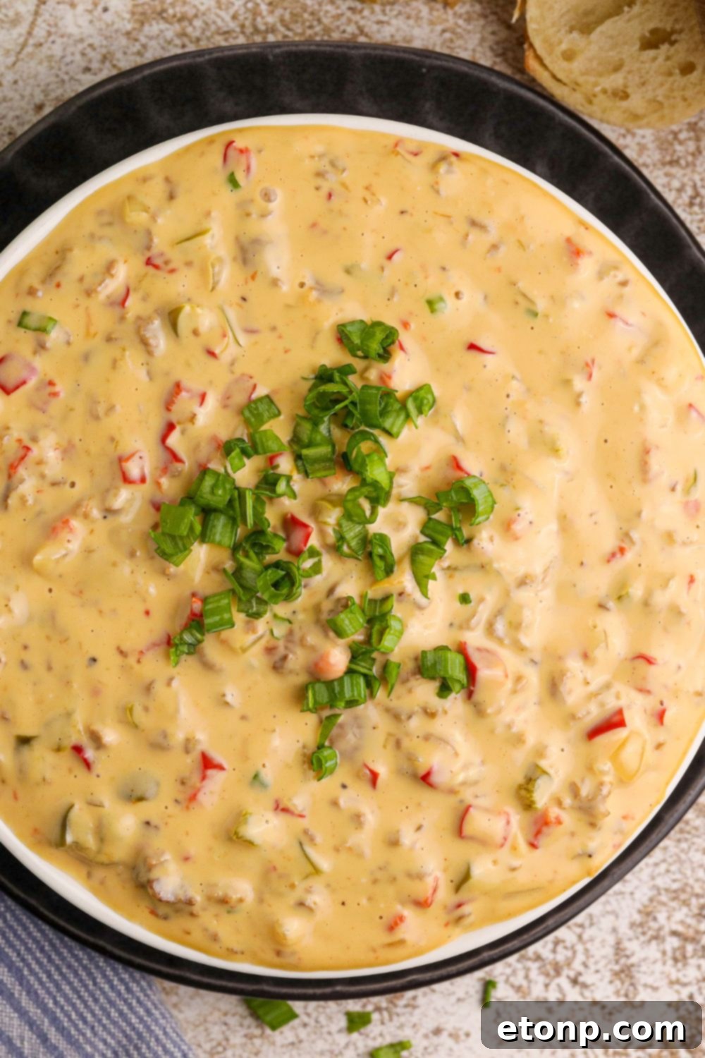 Crock Pot Philly Cheesesteak Dip in a black bowl with some green garnish on top of it 