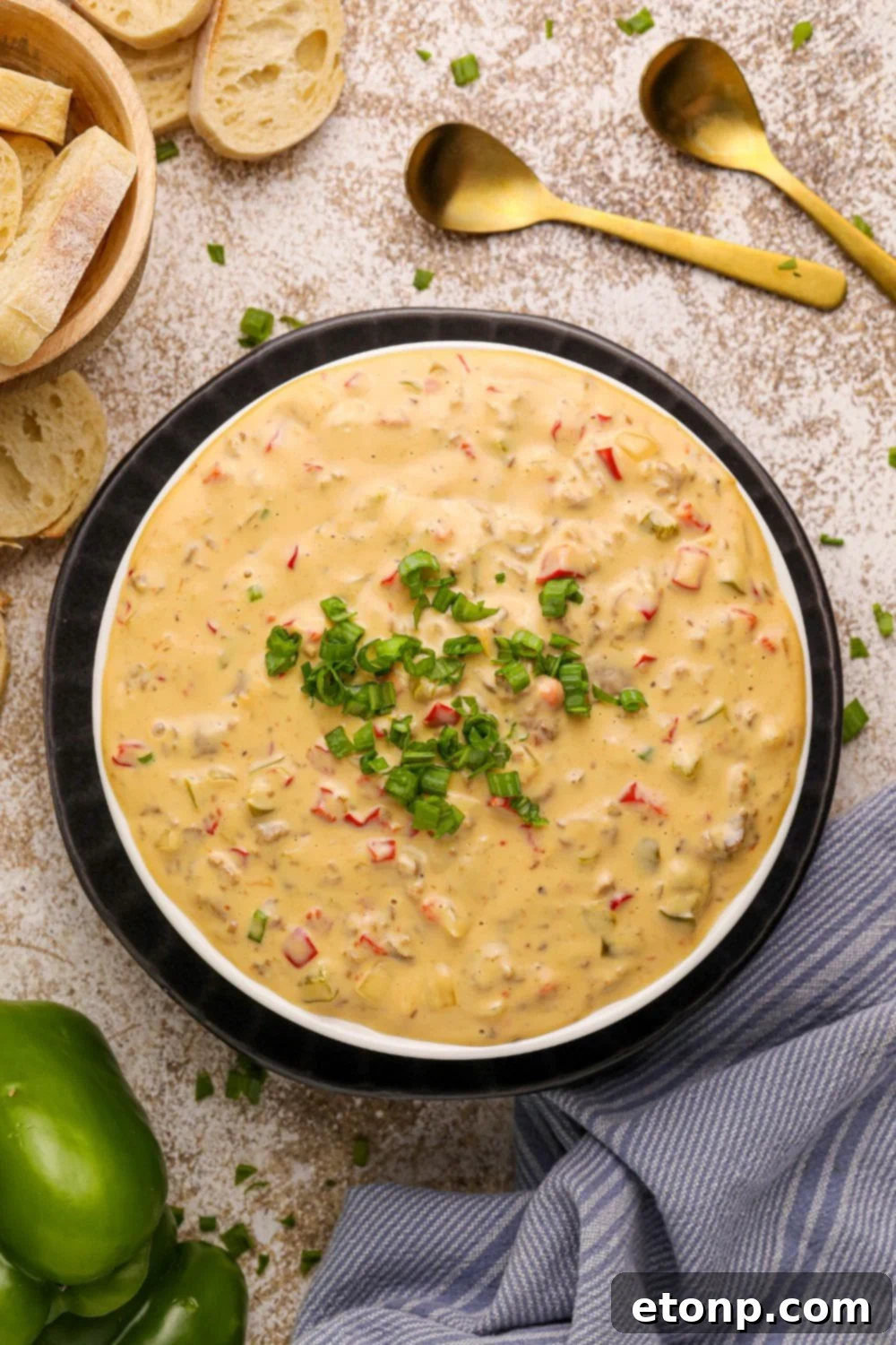 Crock Pot Philly Cheesesteak Dip in a black bowl with sliced bread and a towel around the bowl on counter 