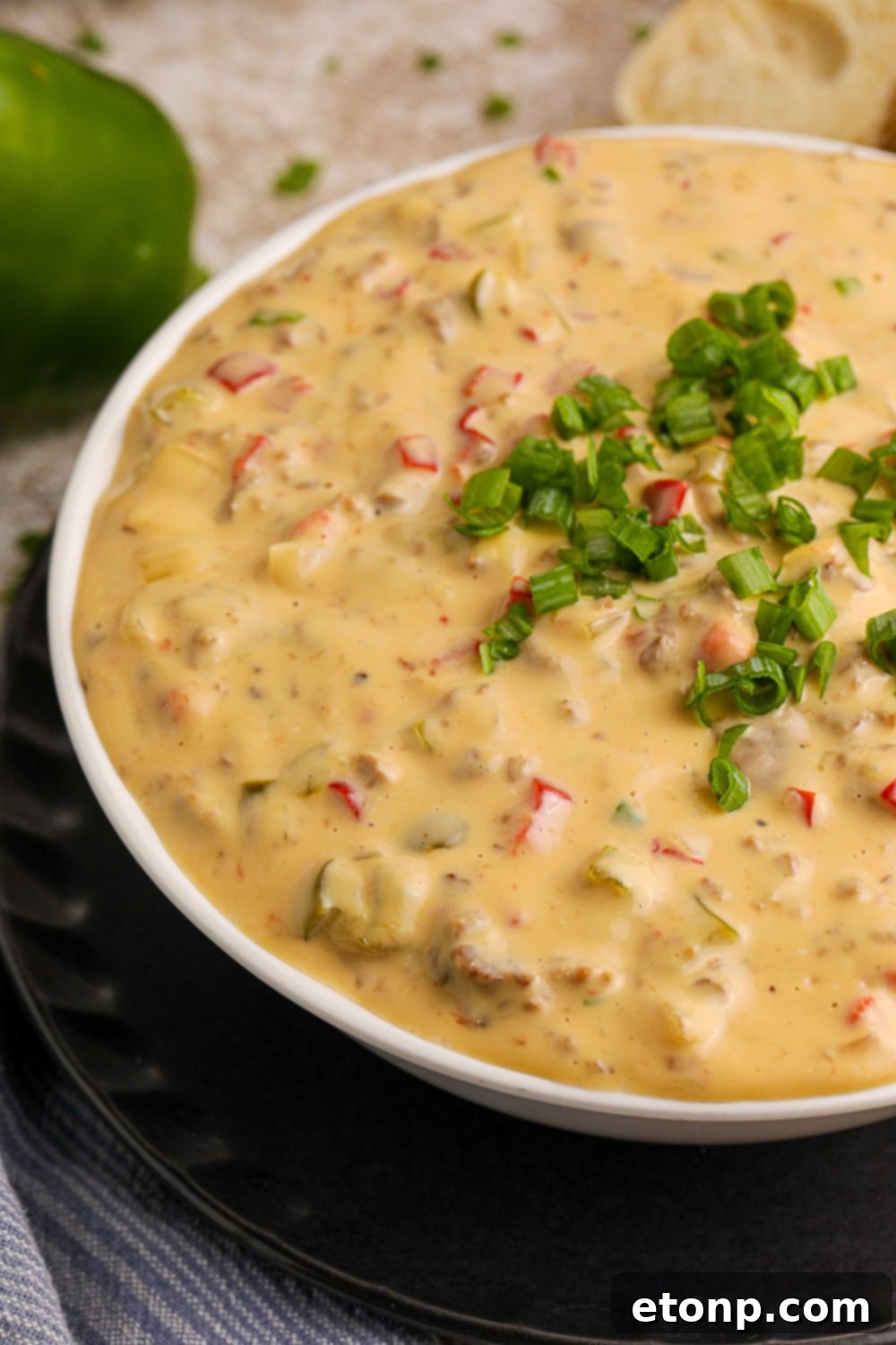 Crock Pot Philly Cheesesteak Dip in a glass bowl on the table, showing only half of the bowl on table 