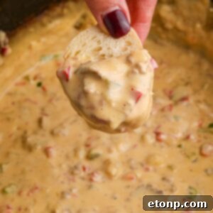 Crock Pot Philly Cheesesteak Dip on a piece of bread in hand over the crockpot full of dip