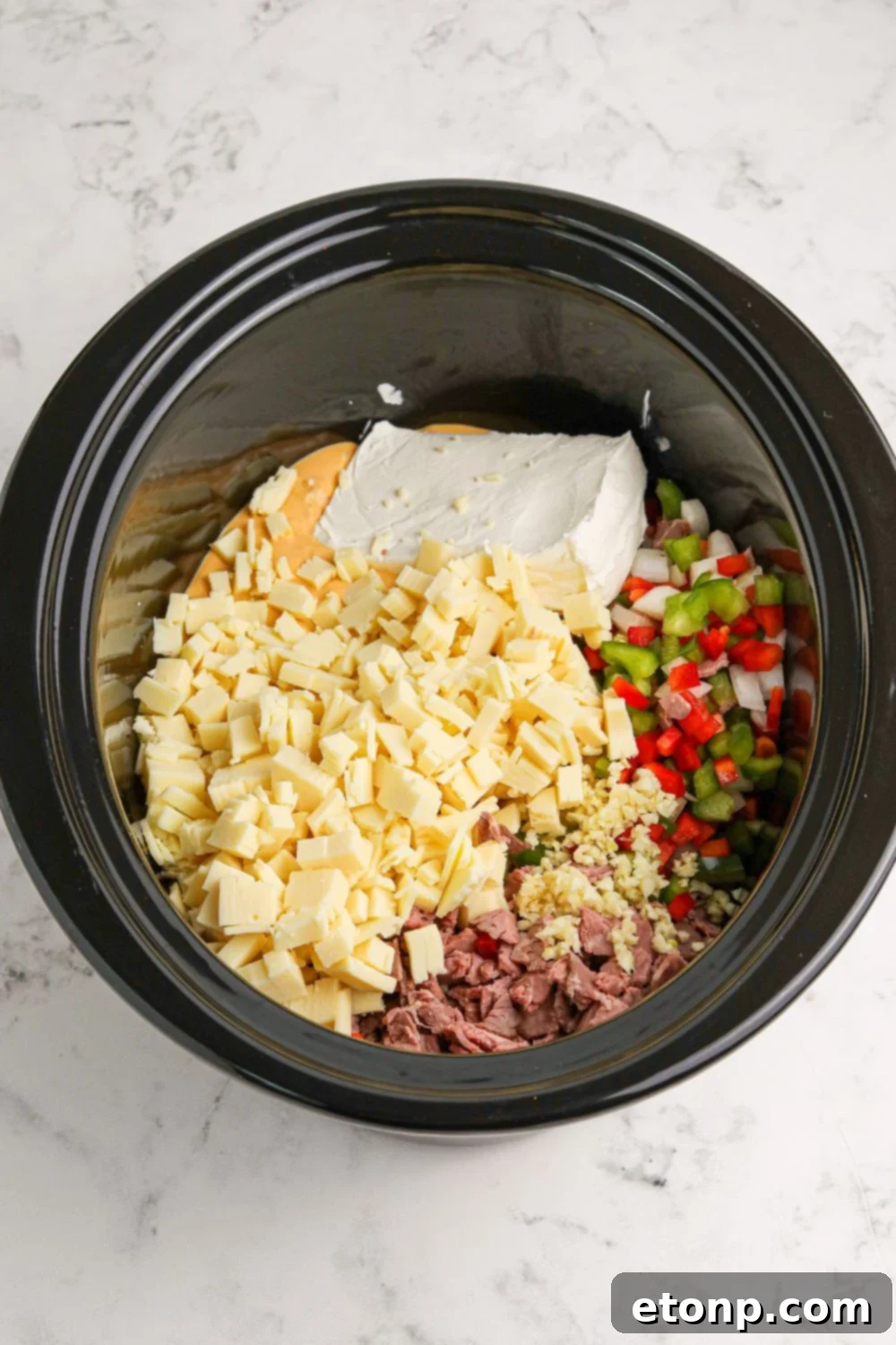 Crock Pot Philly Cheesesteak Dip ingredients in the slow cooker above the pan 