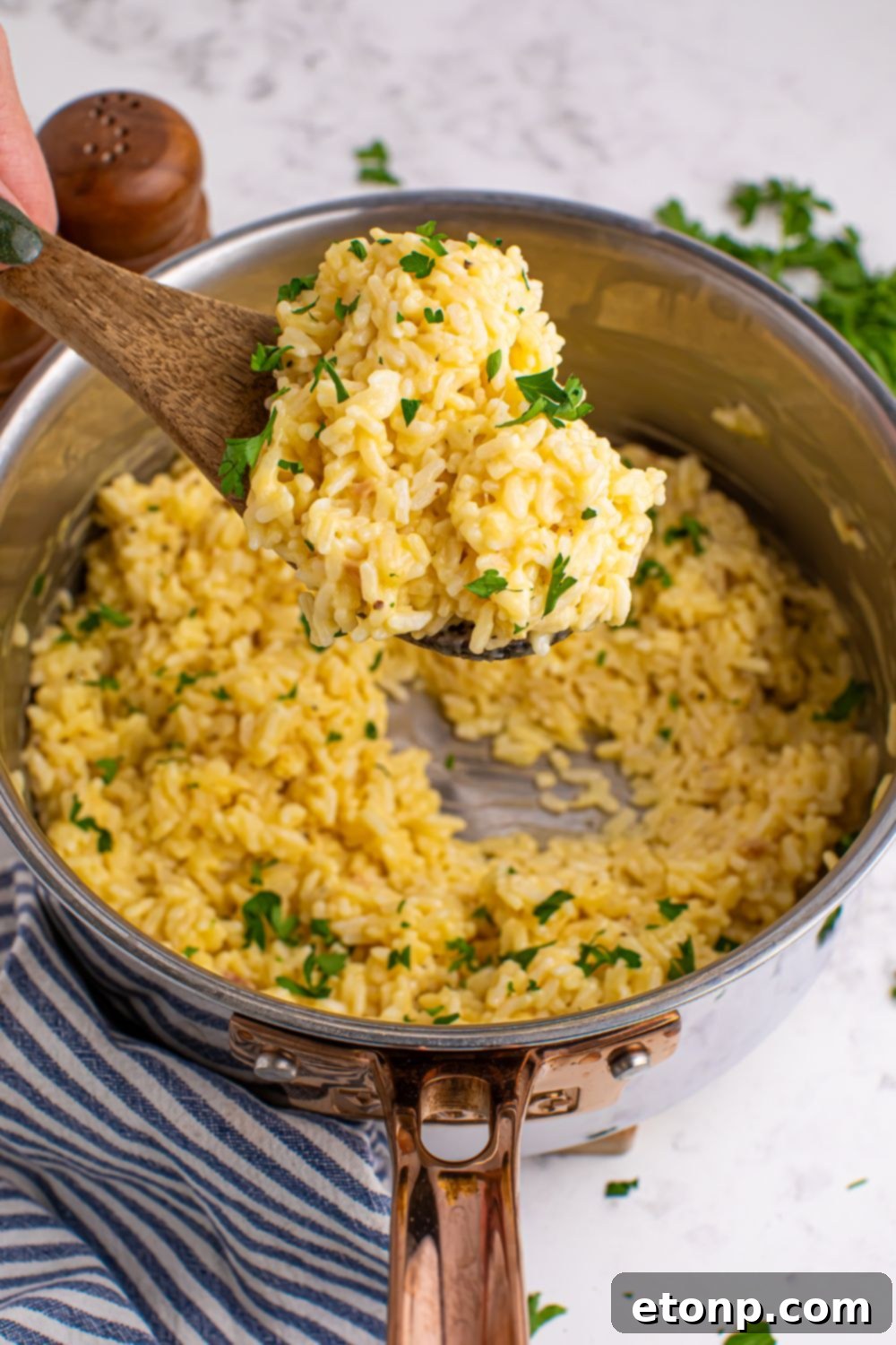 Souper Rice in pan with a wooden spoon full of rice above pan being held by a hand 