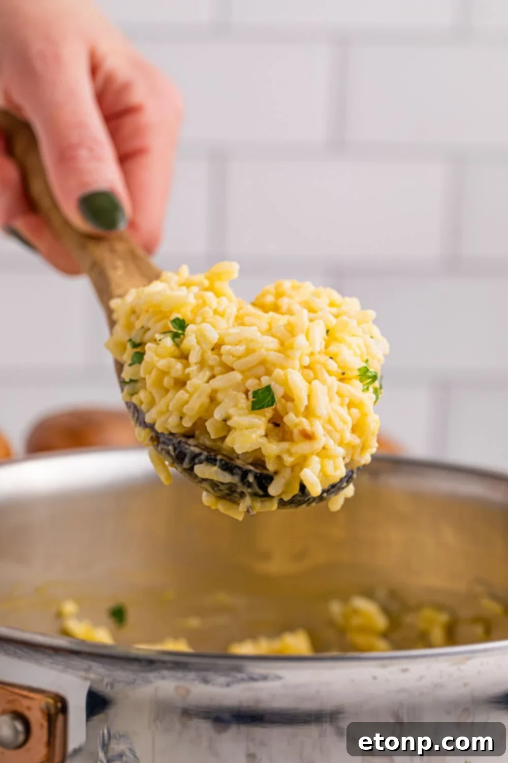 Souper Rice in a plastic spoon being held in a hand above metal pan full of rice 