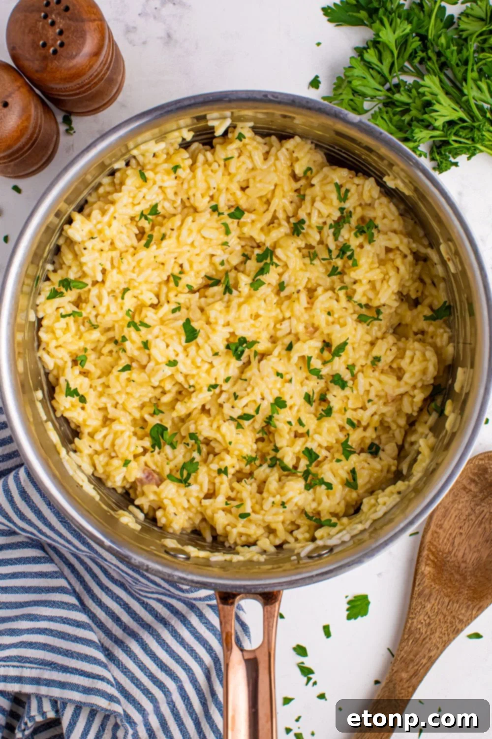 Souper Rice in a metal pan on table with parsley beside it and a wooden spoon 