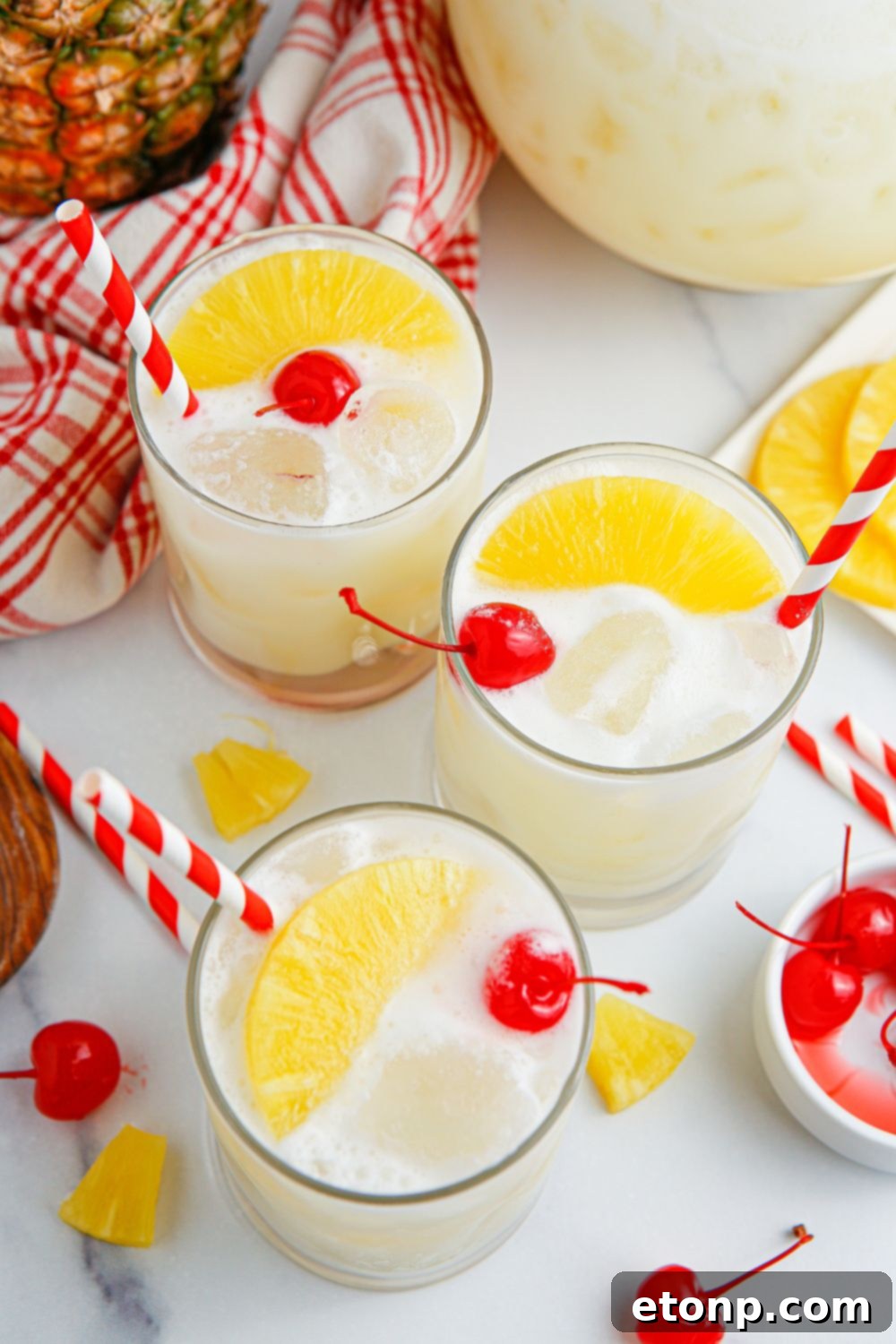 Three glasses with Pina Colada Punch, garnished on top of each glass, on a table.