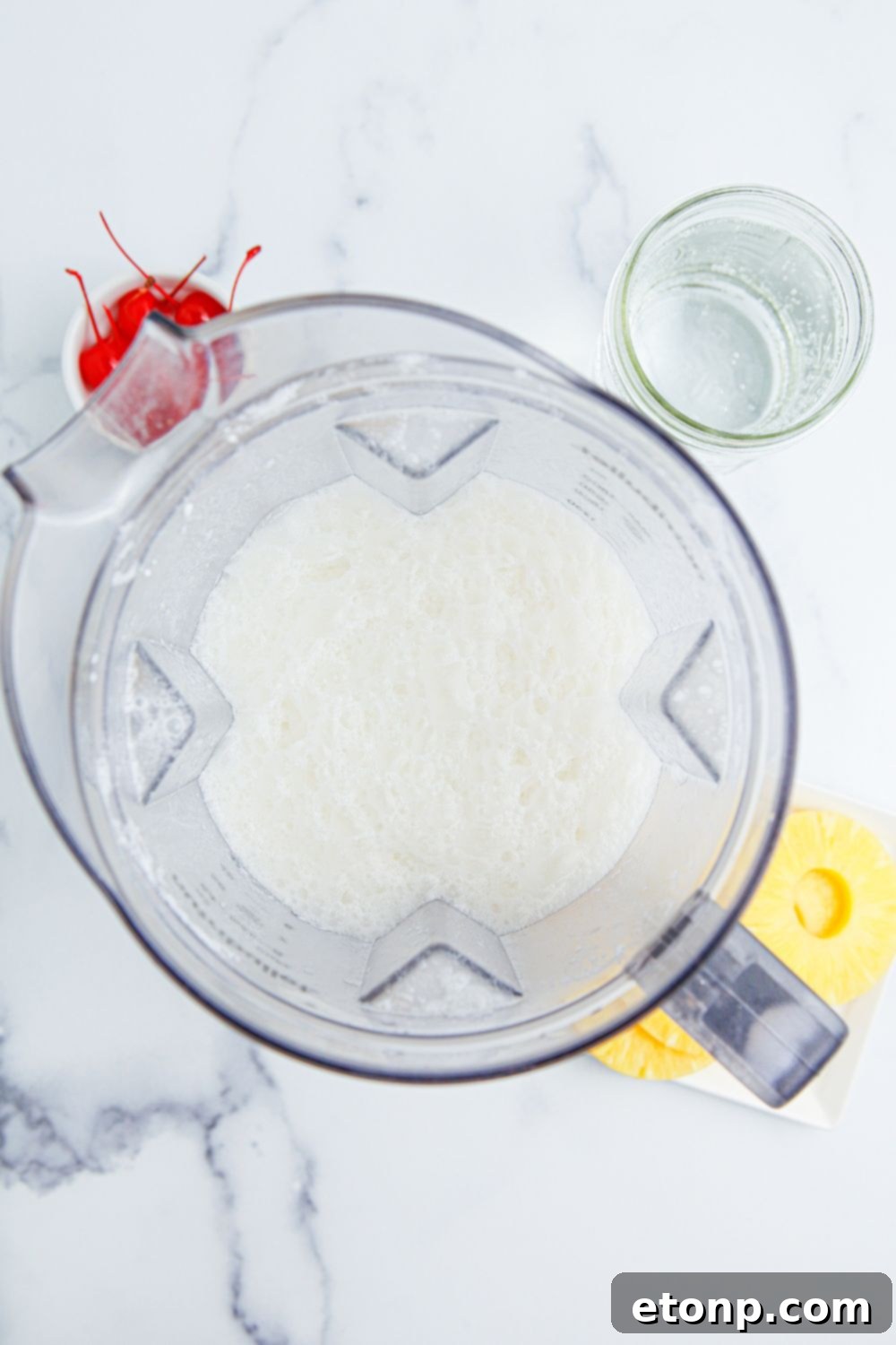 Pina Colada Punch ingredients being blended in a blender on a kitchen table.