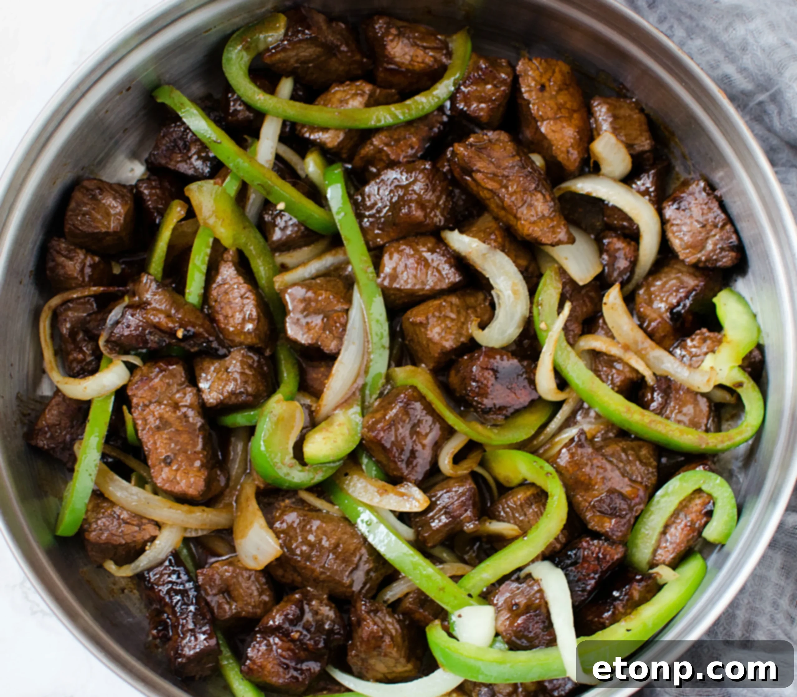 Close-up of freshly cooked Asian steak with vibrant peppers and onions, ready to serve.