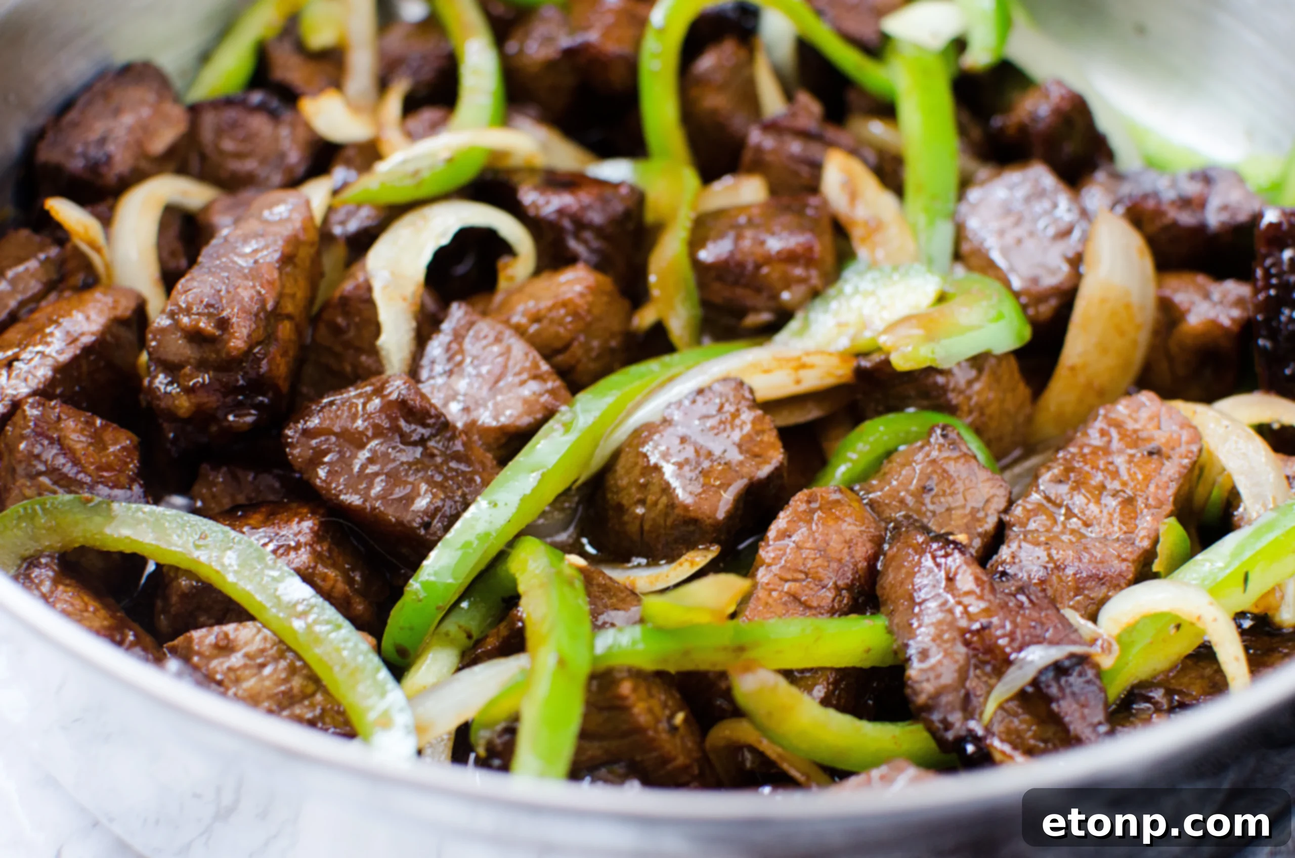 Stir-frying the Asian steak with peppers and onions until perfectly browned and cooked through.